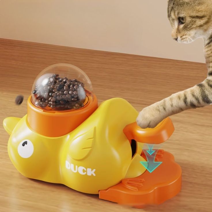 Cat playing with a yellow duck-shaped toy in order to eat.